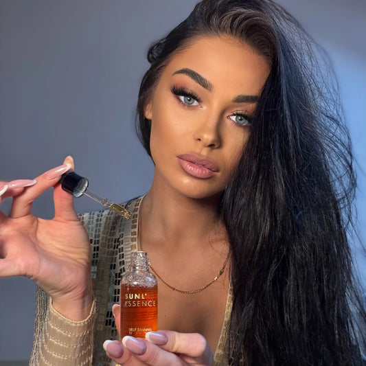 Woman holding a pipette with self-tanning drops above her open palm while preparing to mix it with face cream