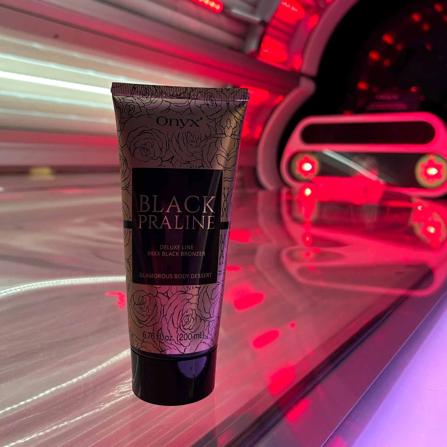 Onyx Black Praline tanning cream standing in red light of a modern sunbed, glossy surface reflecting the glow