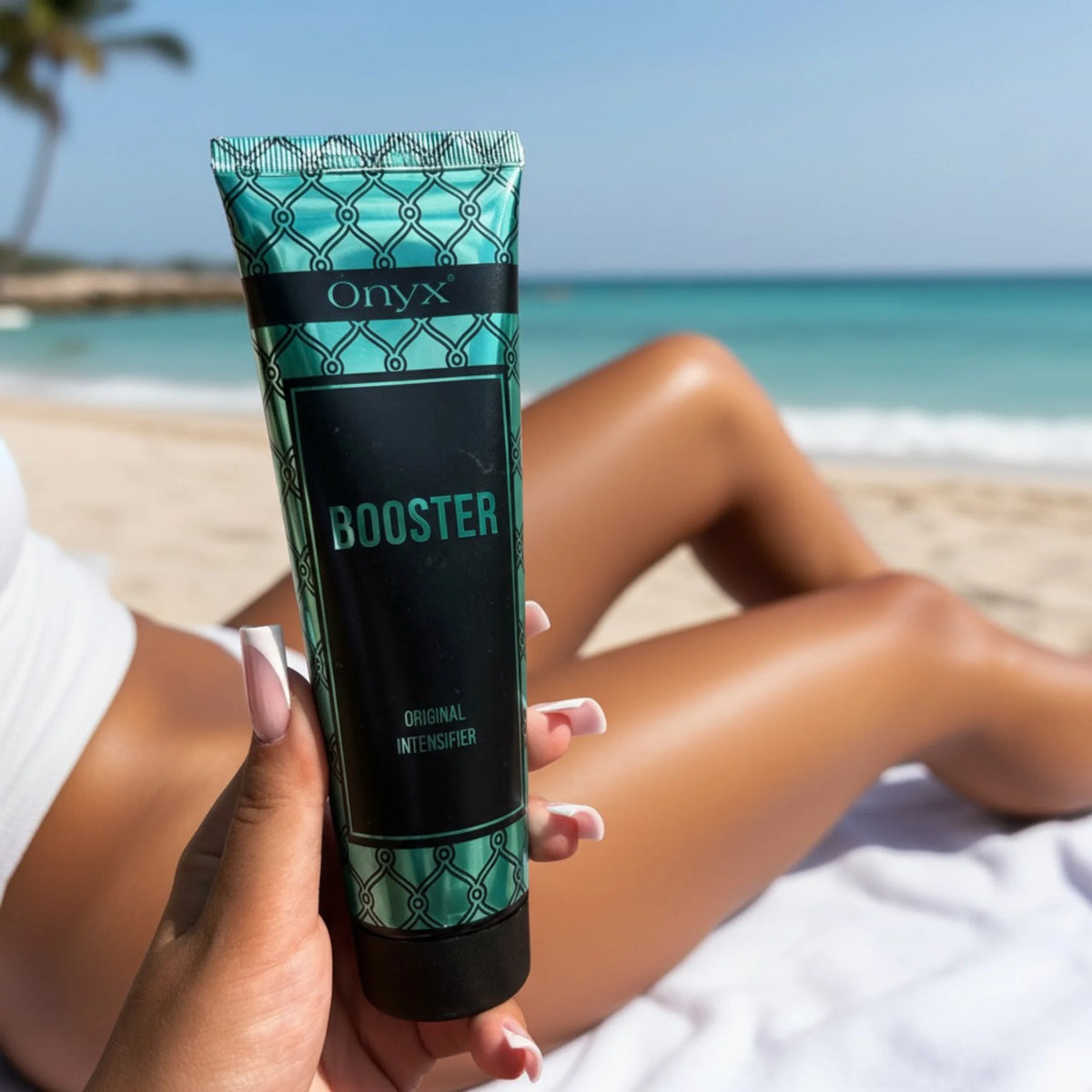 Close-up of an Onyx Booster Original Intensifier tube held on a beach, with the sea and a reclining model in the background.