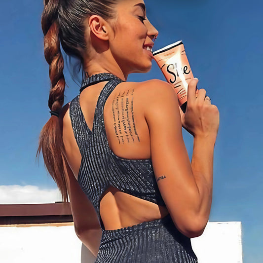 Athletic woman outdoors in sportswear holding Onyx She bronzing cream while smiling against a blue sky