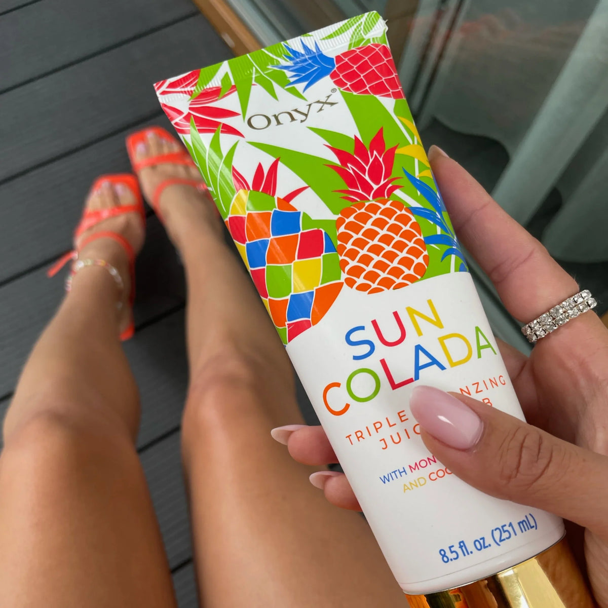 Onyx Suncolada tanning accelerator cream focused on legs with red shoes in background