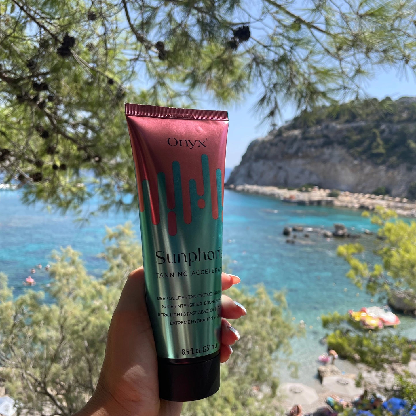 Onyx Sunphoria tanning accelerator cream held outdoors with sea view, perfect for sun tanning