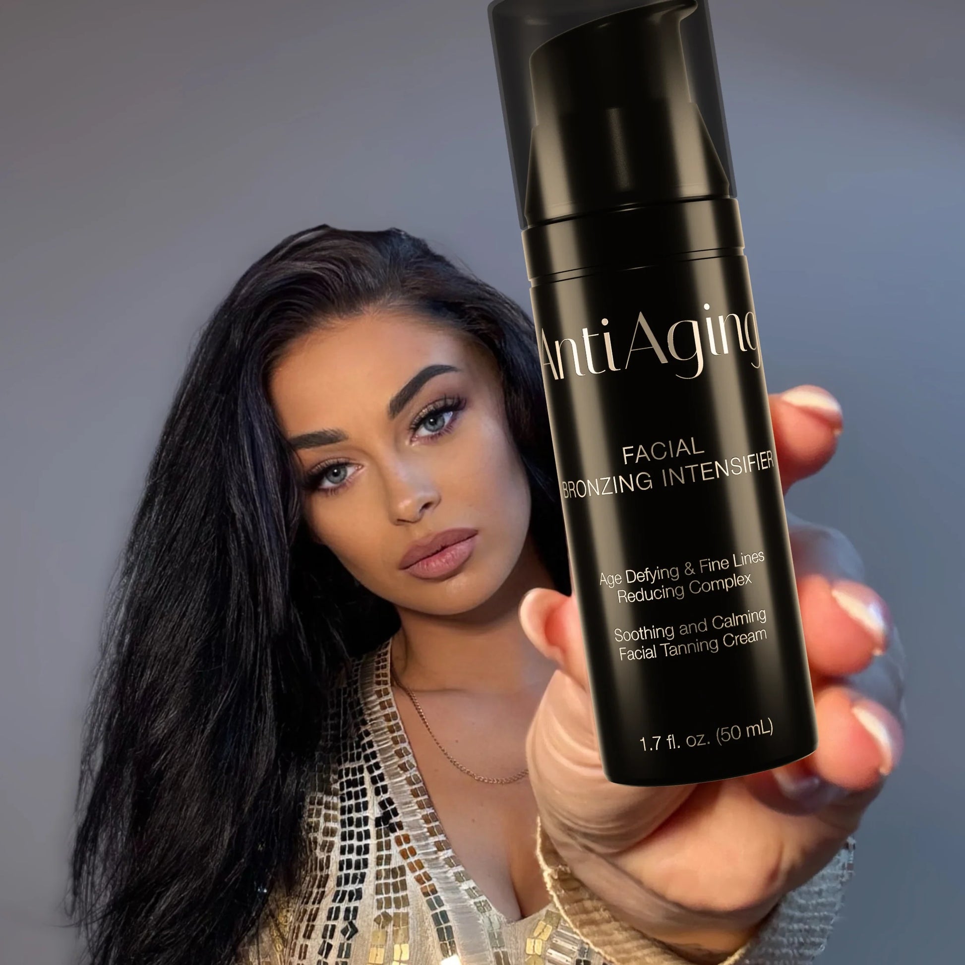 Woman holding a black bottle of Onyx Anti-Ageing cream towards the camera with a neutral background