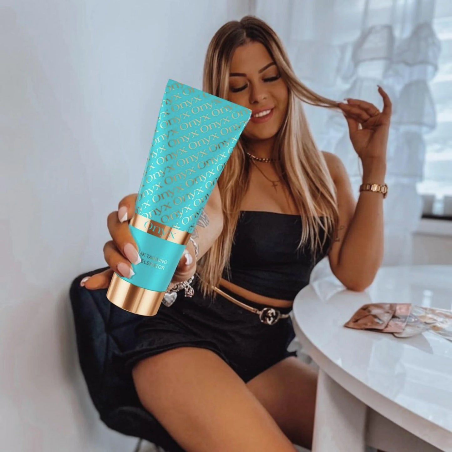 Woman indoors holding Onyx Dark Tanning Accelerator tanning cream for faster results