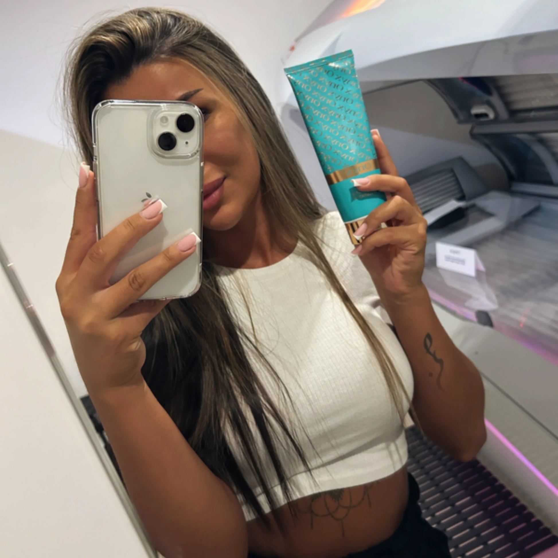Woman in tanning bed holding Onyx Dark Tanning Accelerator cream for deeper tan results