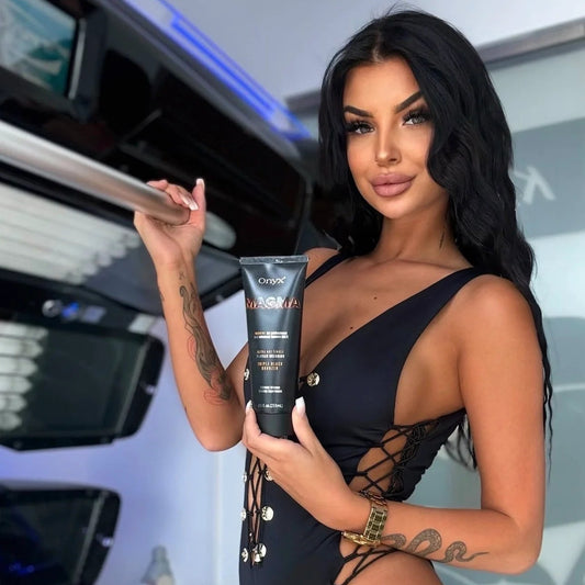 Model holding an Onyx Magma tanning lotion tube beside an open sunbed while wearing a black swimsuit.