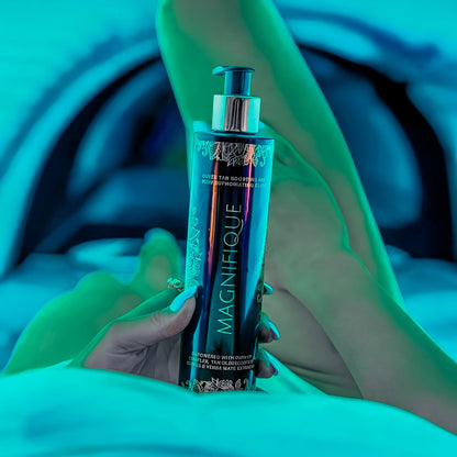 Close-up of a hand holding Onyx Magnifique cream with legs in the background under blue UV light