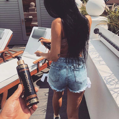 Outdoor scene with a man holding Onyx Magnifique cream while a woman in denim shorts applies lotion near sunbeds