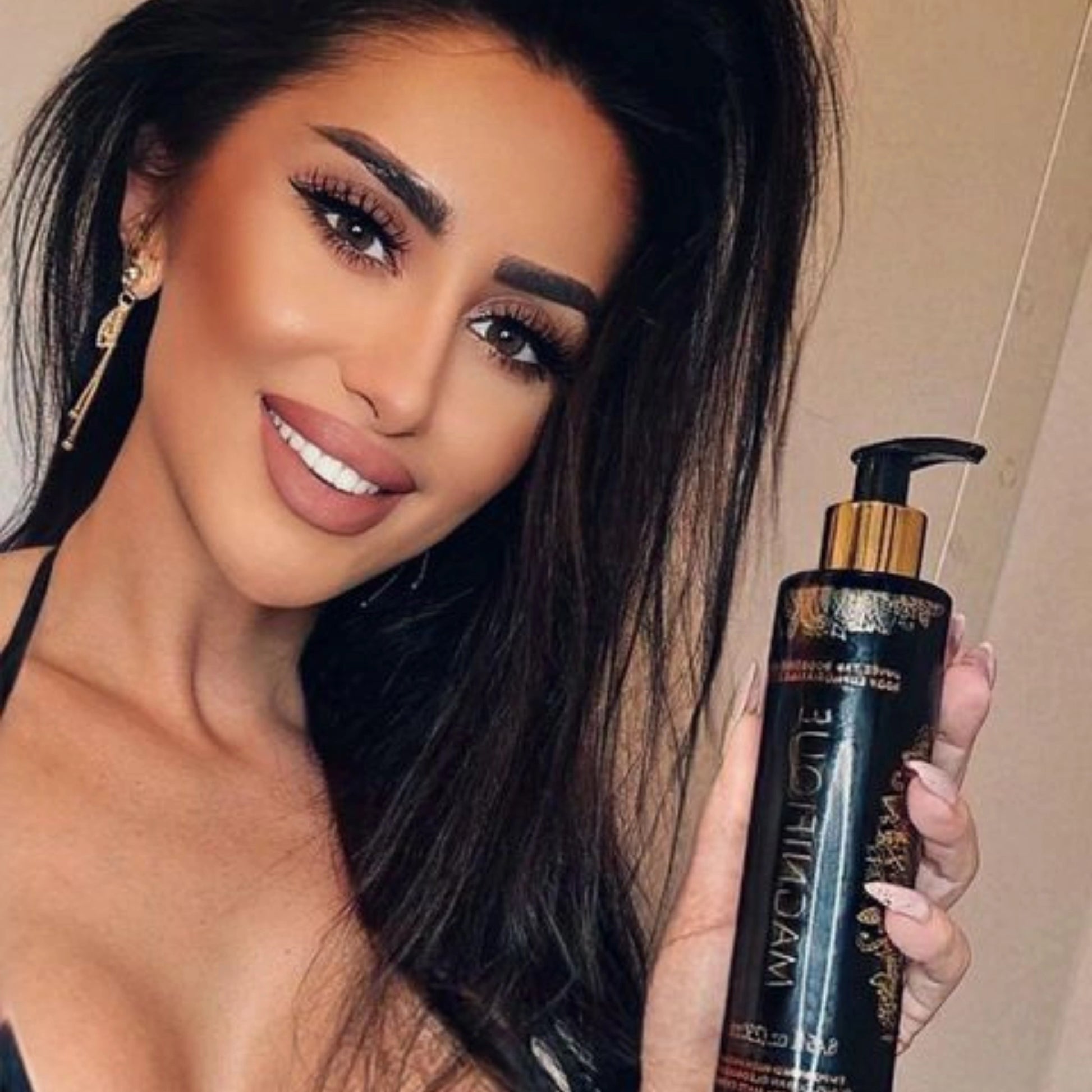 Smiling woman with long dark hair holding Onyx Magnifique cream close to the camera
