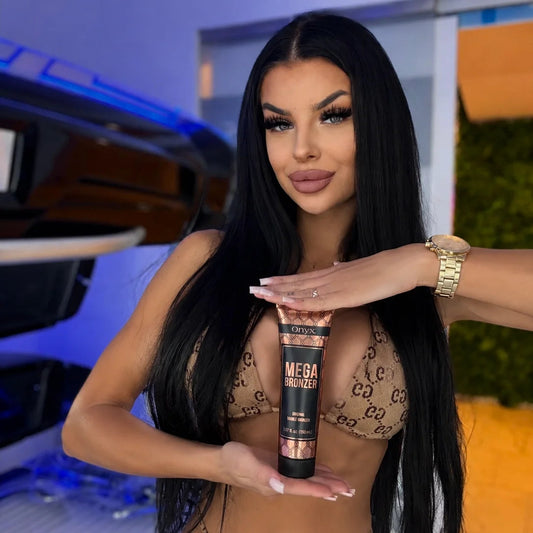 Model holding an Onyx Mega Bronzer cream in front of an open sunbed while wearing a patterned bikini.