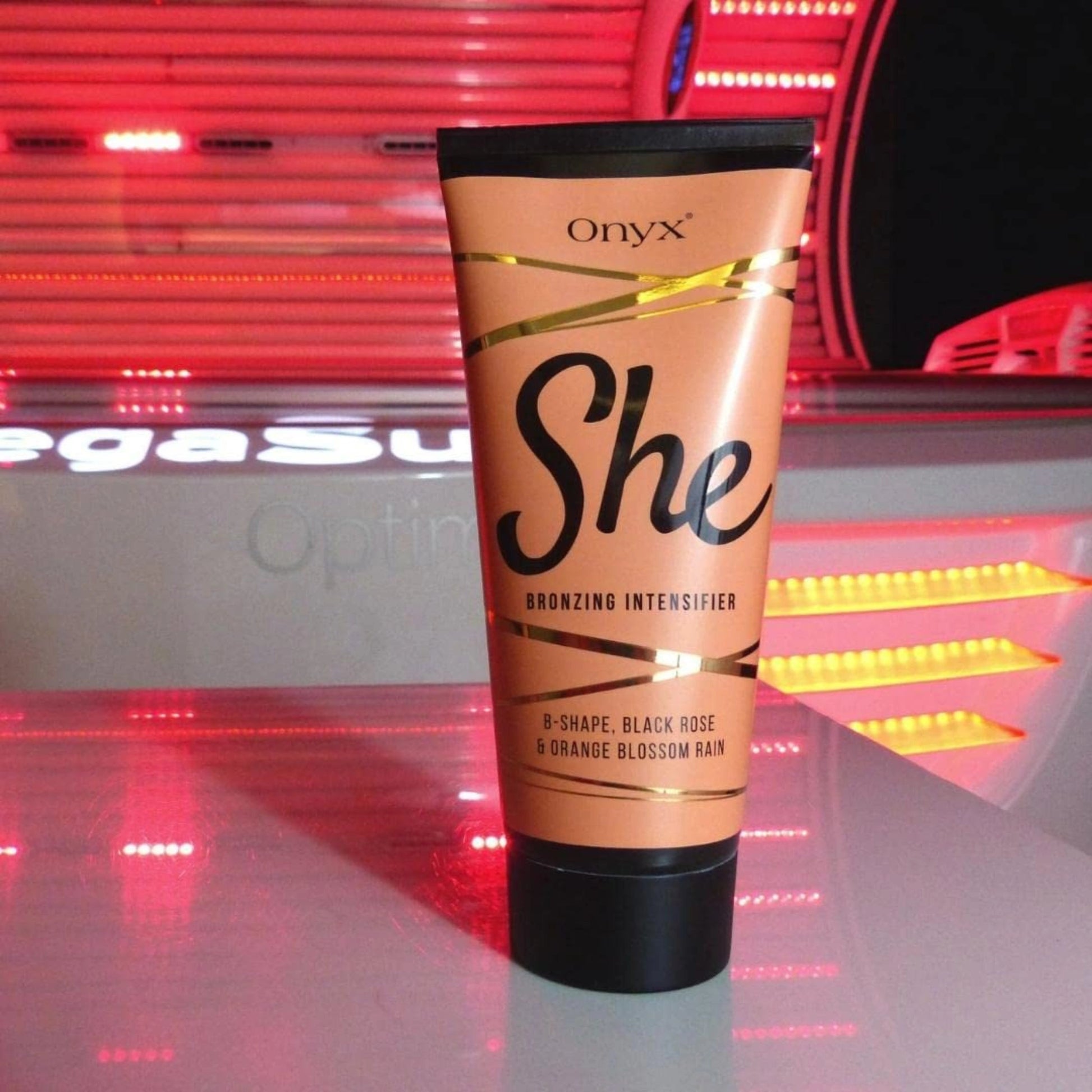 Onyx She Bronzing Intensifier cream placed on a red-lit tanning bed surface