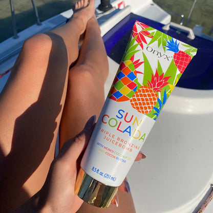 Onyx Suncolada sunbed accelerator cream displayed on tanned legs in sunlight on yacht