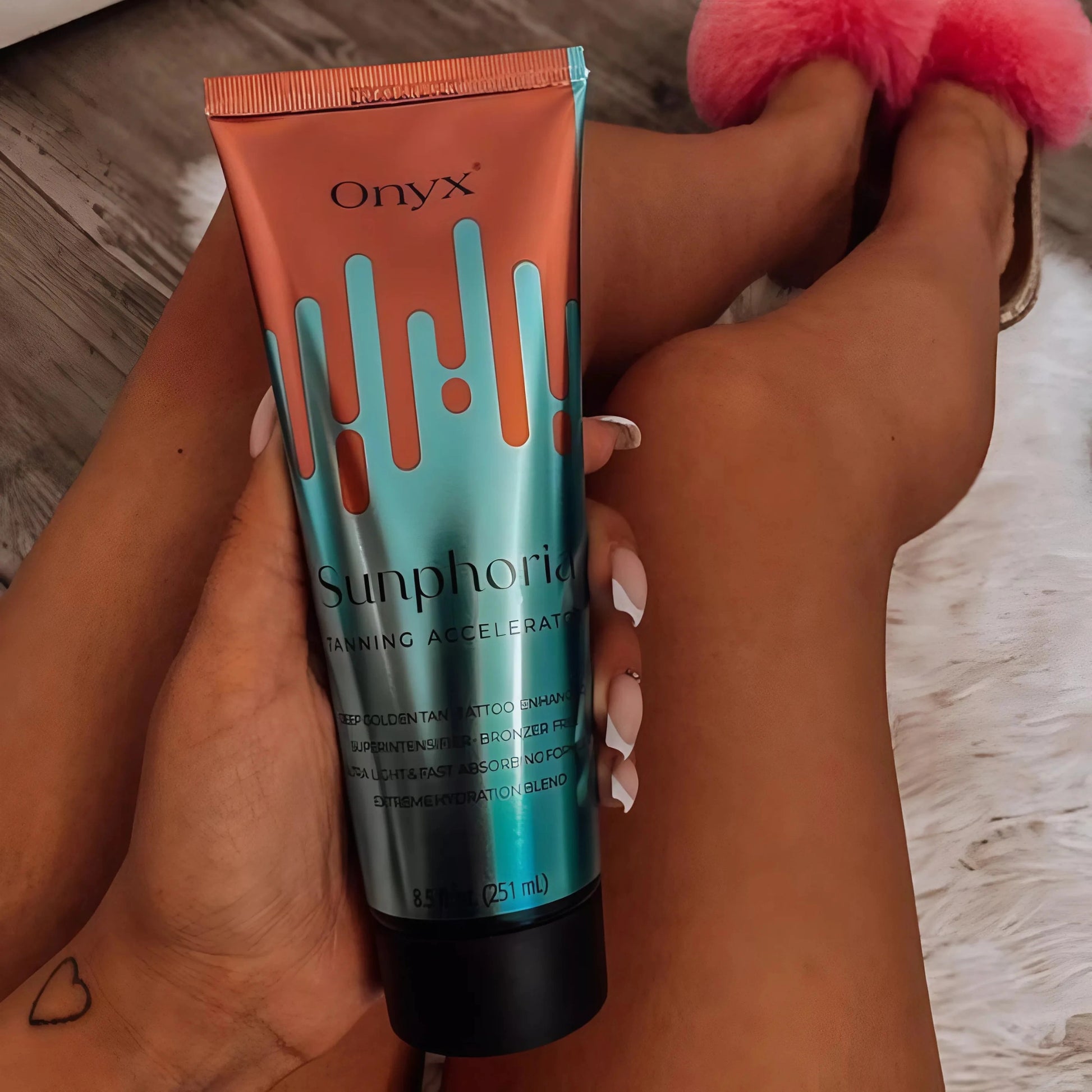 Hand holding Onyx Sunphoria sunbed tanning accelerator cream with tanned legs on display