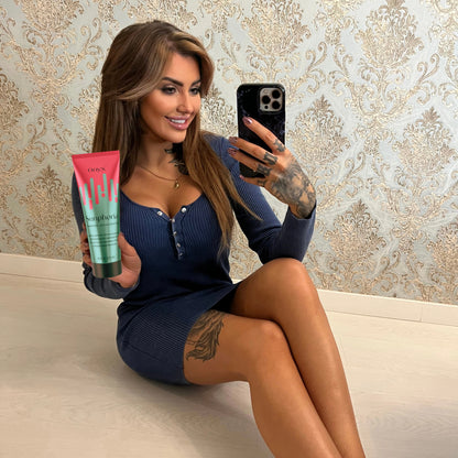 Tattooed woman taking mirror selfie with Onyx Sunphoria sunbed tanning accelerator cream