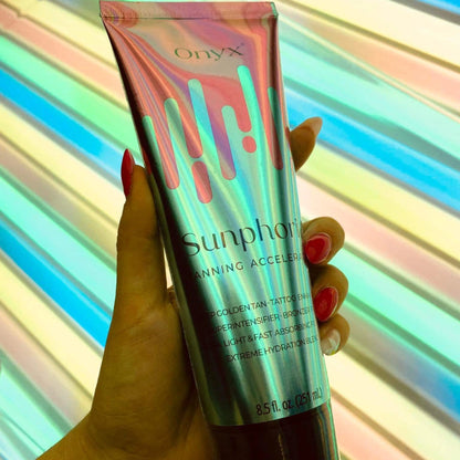 Hand holding Onyx Sunphoria sunbed accelerator cream under UV tanning bed lights indoors