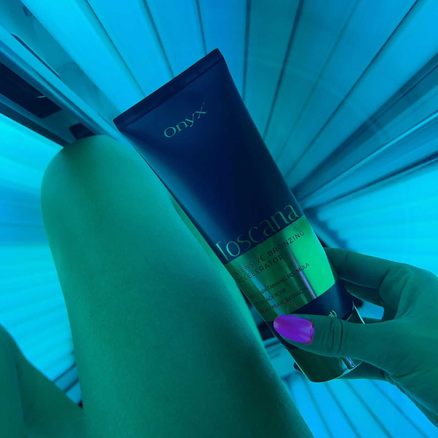 Close-up of a woman’s leg and Onyx Toscana bronzing cream inside a blue-lit sunbed
