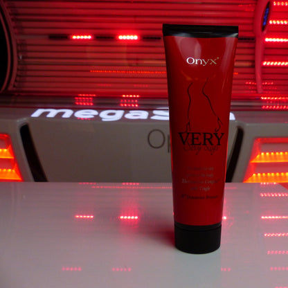 Onyx Very Sexy Legs tingle bronzer cream placed on a surface in front of a glowing red sunbed