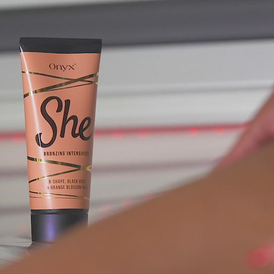 Women applying Onyx She tanning cream, showing smooth glowing skin and the product tube in bright, elegant surroundings